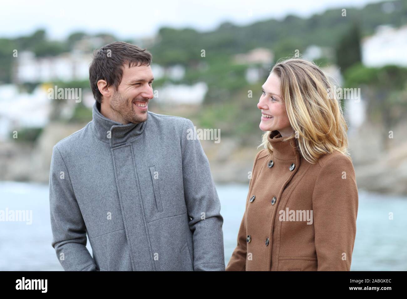 Felice l'uomo e donna che parlano e camminare sulla spiaggia in inverno Foto Stock