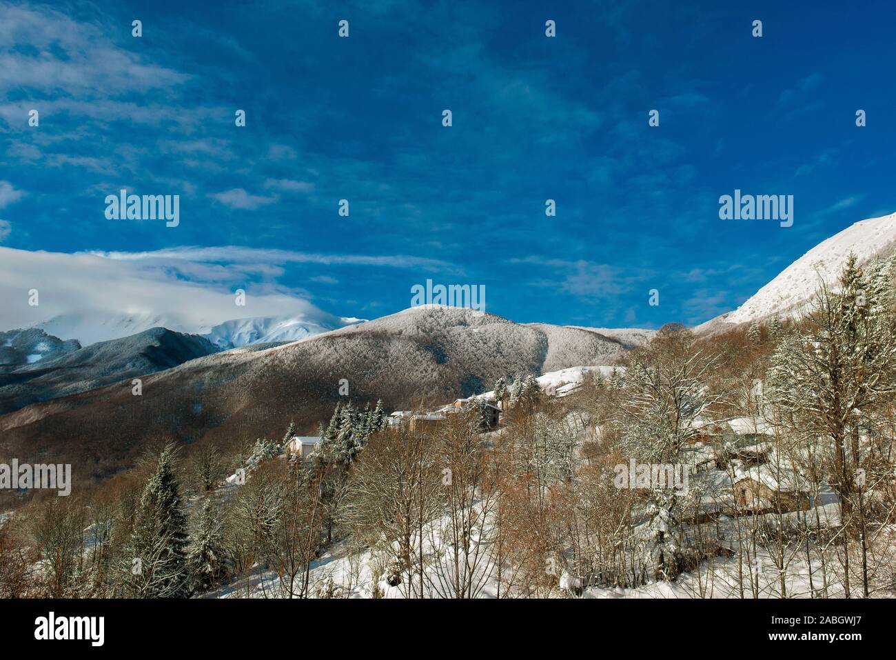 Emilia Romagna - da poco sopra l'abitato di Monte Orsaro, una vista complessiva della piccola montagna con il Monte Cusna appena a sinistra del centro con la cima coperta da una nuvola: sotto il villaggio di Monte Orsaro Foto Stock