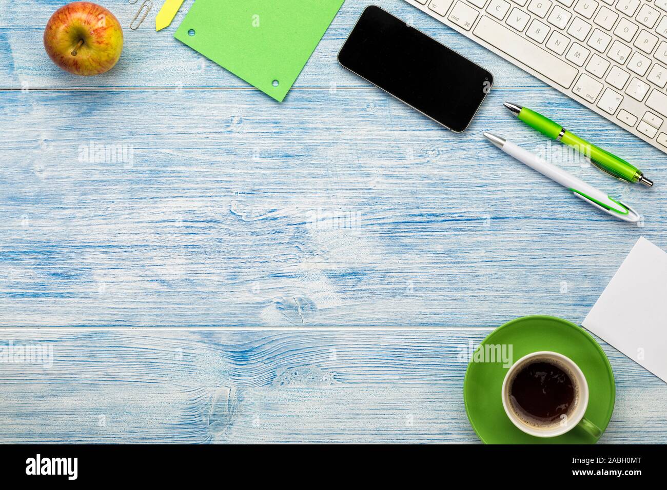 Sfondo con la tastiera del computer, smart phone, tazza di caffè e utensili disposti su blu scrivania in legno. Copia di grandi dimensioni spazio. Foto Stock