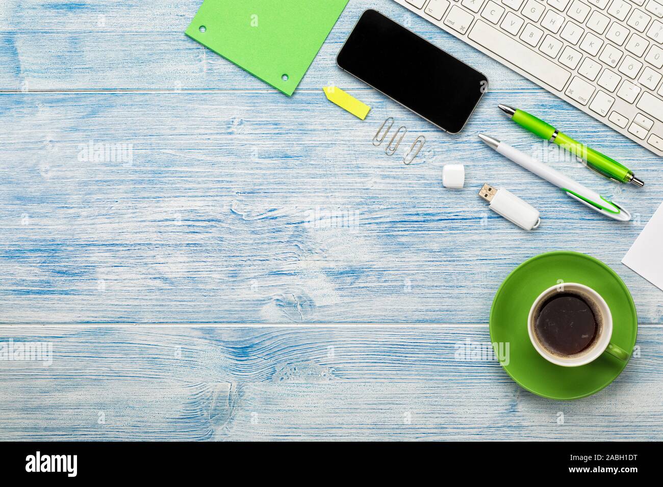 Sfondo con la tastiera del computer, smart phone, tazza di caffè e utensili disposti su blu scrivania in legno. Copia di grandi dimensioni spazio. Foto Stock