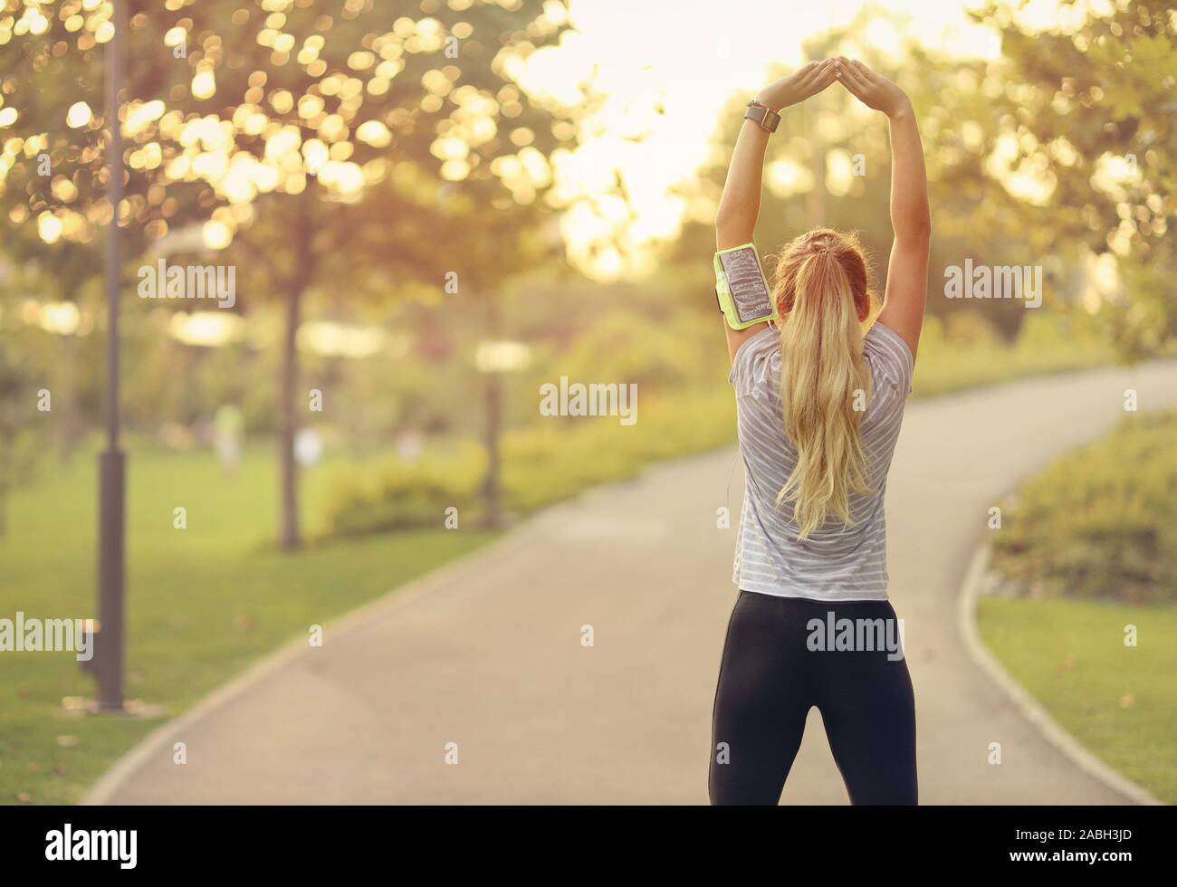 Montare la giovane donna in esecuzione nel parco - attraente femmina bionda facendo esercizi di stretching esterni - uno stile di vita sano concetto Foto Stock