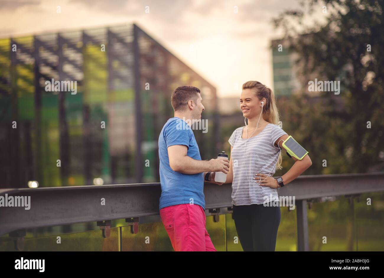 Giovane riposo dopo esercizio nel parco - uomo e donna la formazione all'aperto e divertirsi dopo allenamento durante il tramonto in una giornata di sole - sportivo amici a poppa Foto Stock