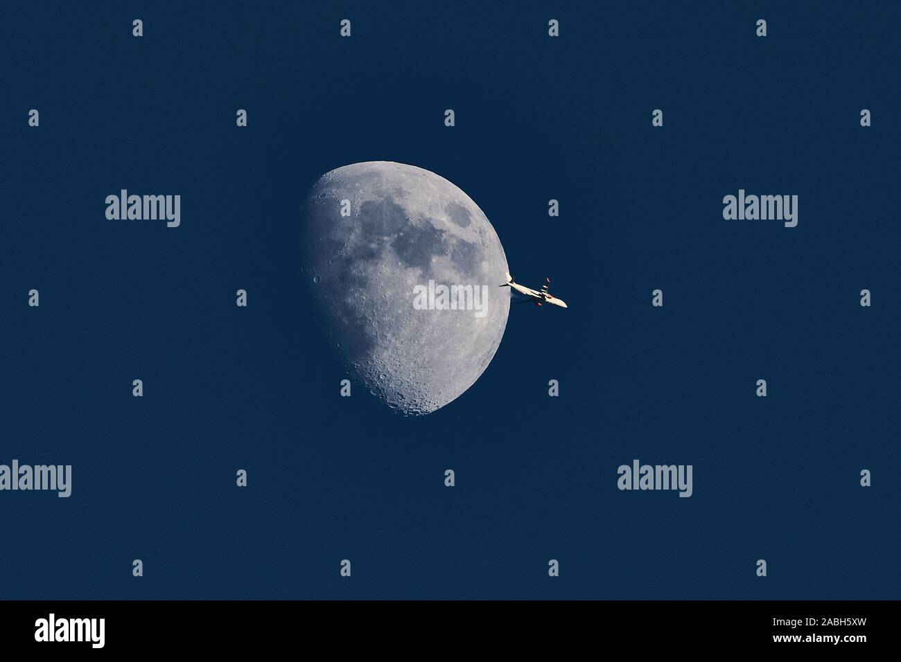 Aeroplano passando la luna crescente di sera la luce diurna Foto Stock