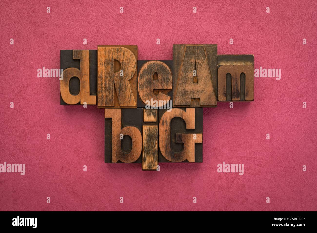 Grande sogno, una frase scritta con l'annata tipografia blocchi su texture di sfondo di colore rosa. Foto Stock