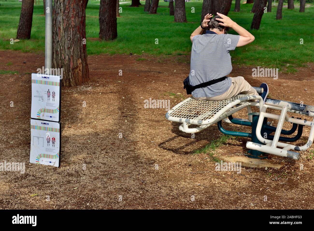 Donna che utilizza attrezzature ginniche in parco pubblico particolarmente rivolto alle persone anziane ma a chiunque di utilizzare Foto Stock