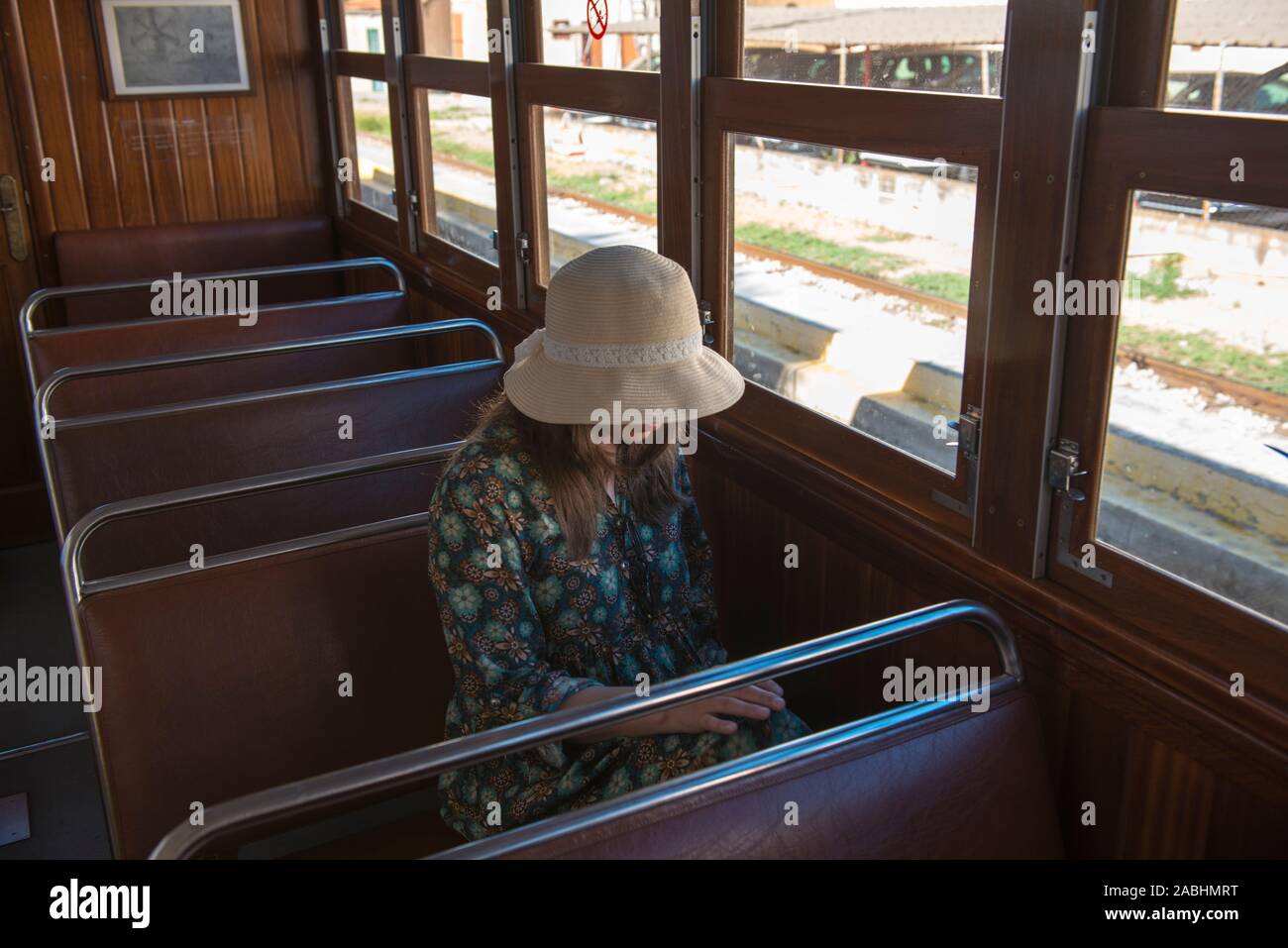 Una donna in abiti vintage e il cappello con le mani su un treno sullo sfondo di una giornata di sole. Ritratto di una donna alla moda in stile retrò. Foto Stock