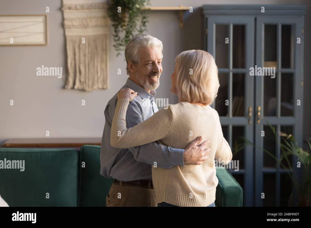 Grey-haired marito abbraccia bionda moglie coppia danzante a casa Foto Stock