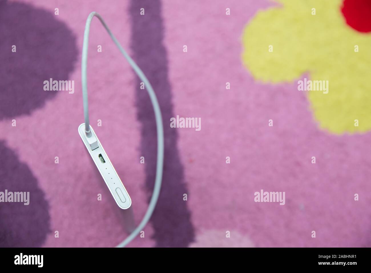 Banca di energia . La ricarica dello smartphone con argento Banca di potenza a spirale attraverso il cavo USB . La ricarica dello smartphone con il potere bancari su pink carpet . Foto Stock