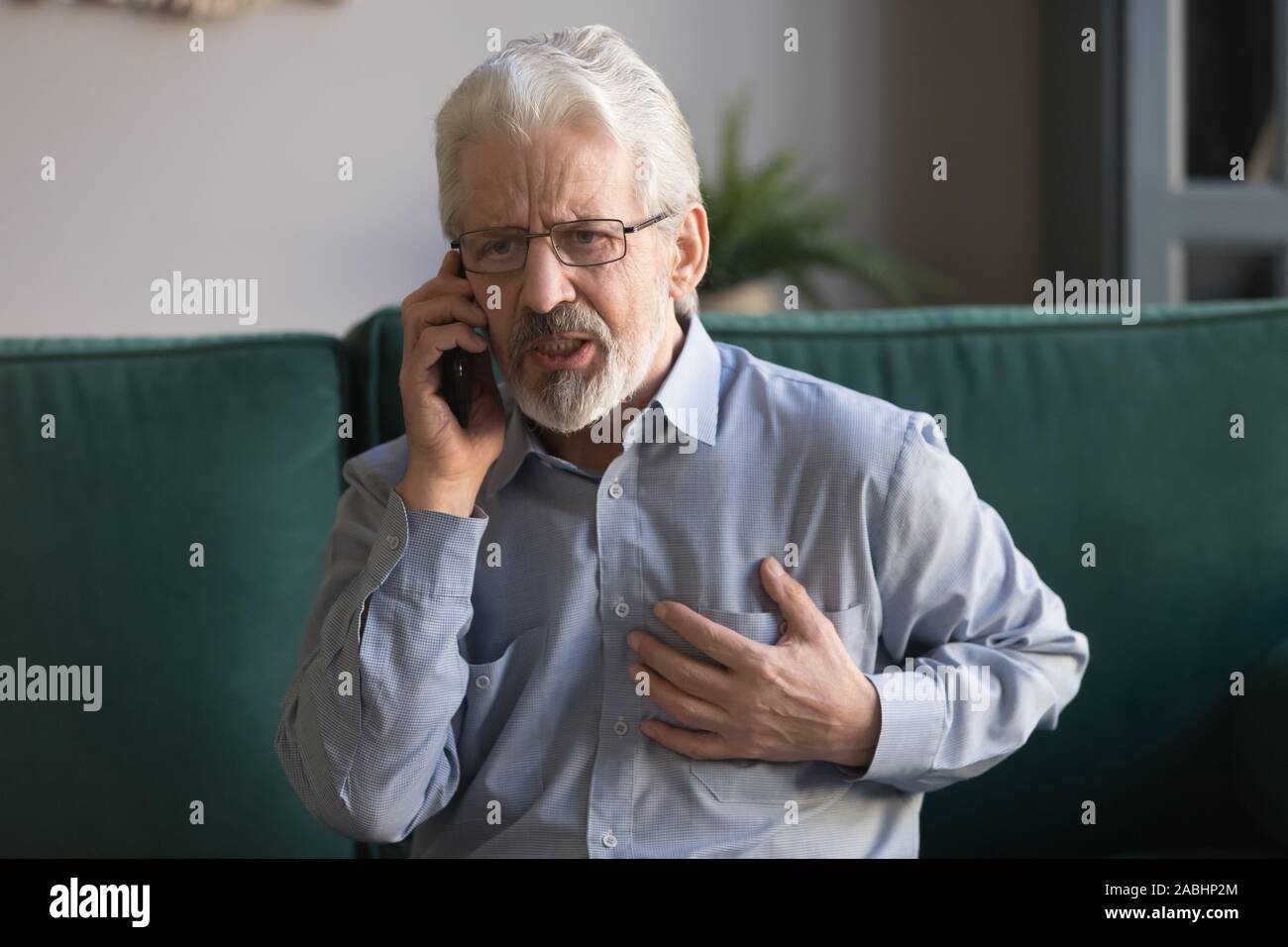 Uomo anziano si sente dolore nel petto chiamare un'ambulanza Foto Stock