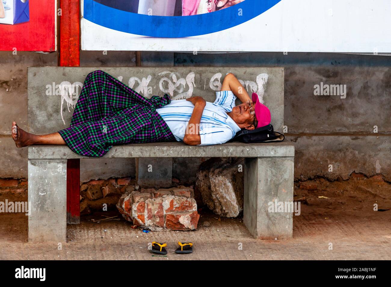 Un Uomo sdraiato su un banco di lavoro in corrispondenza di una stazione ferroviaria, Yangon, Myanmar. Foto Stock