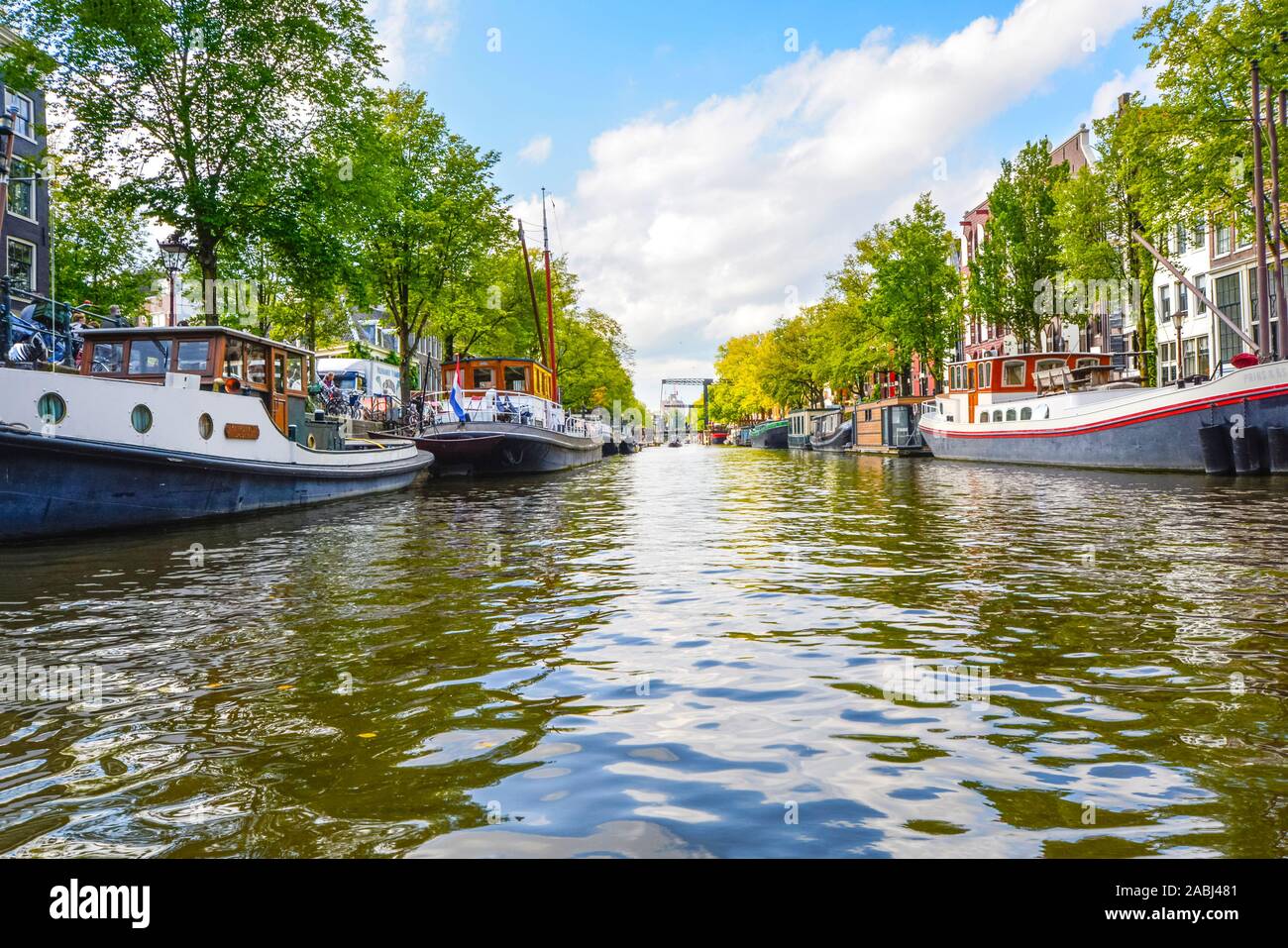 Livello acqua vista da un tour in barca in autunno di un canale residenziale pieno di barche e case galleggianti in Amsterdam, Paesi Bassi. Foto Stock