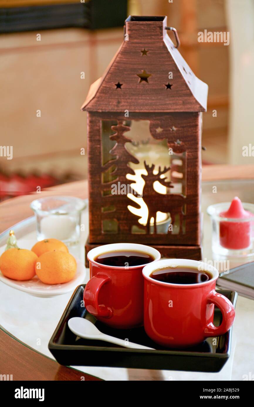 Espresso in festa red tazze con lanterna in rame e mandarine arance in background. Formato verticale. Comfort Hygge concetto. Foto Stock