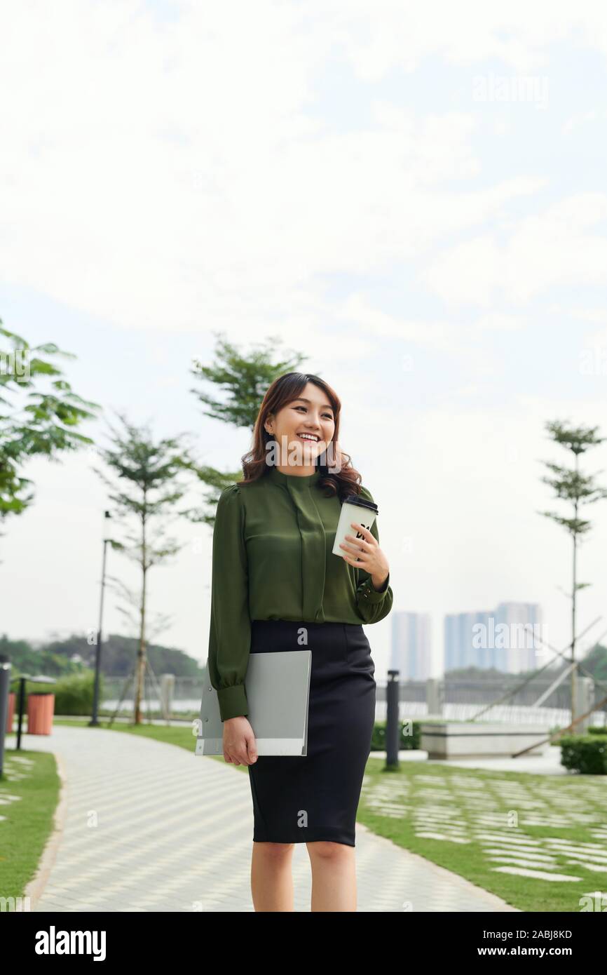 Elegante bsuiness successo donna passeggiate all'aperto con tazza di portar via il caffè Foto Stock