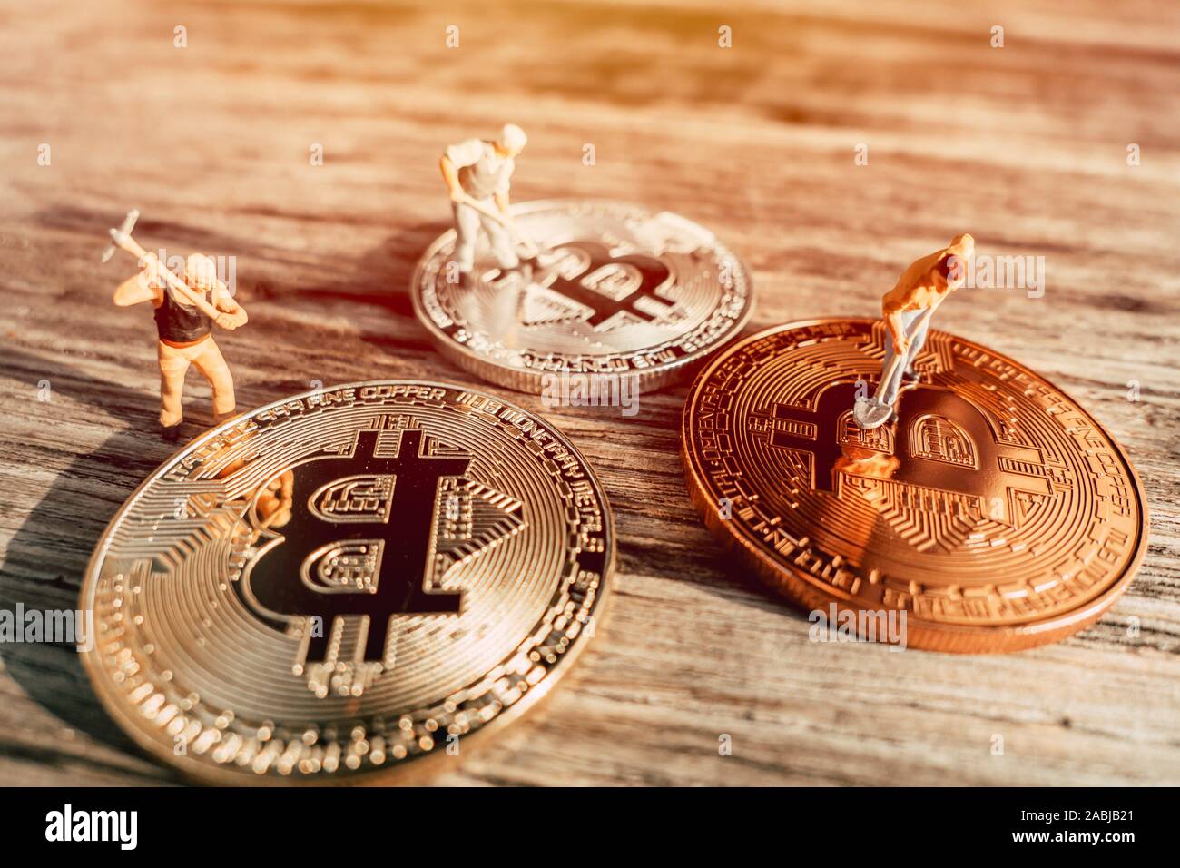 Persone in miniatura denaro lavoratore con Bitcoins monete su uno sfondo di legno per minatore di bit o Bitrig concetto. Foto Stock