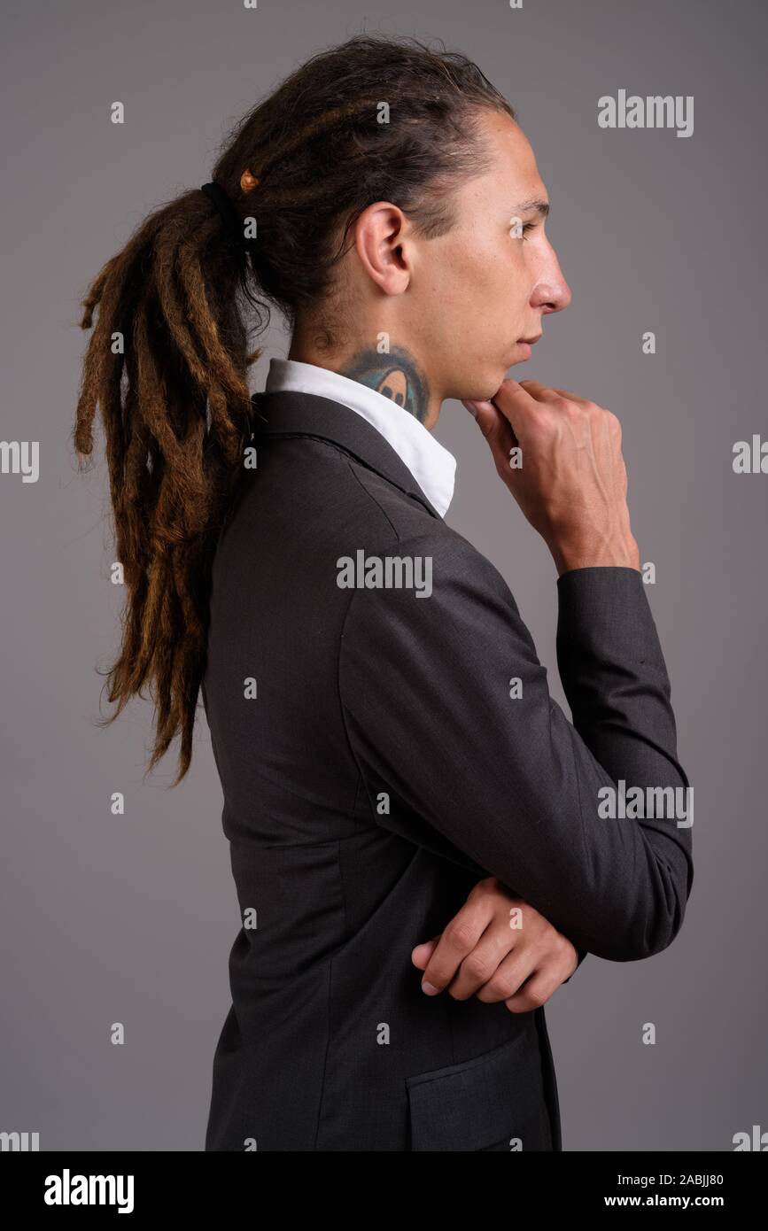 Giovane imprenditore con dreadlocks contro uno sfondo grigio Foto Stock