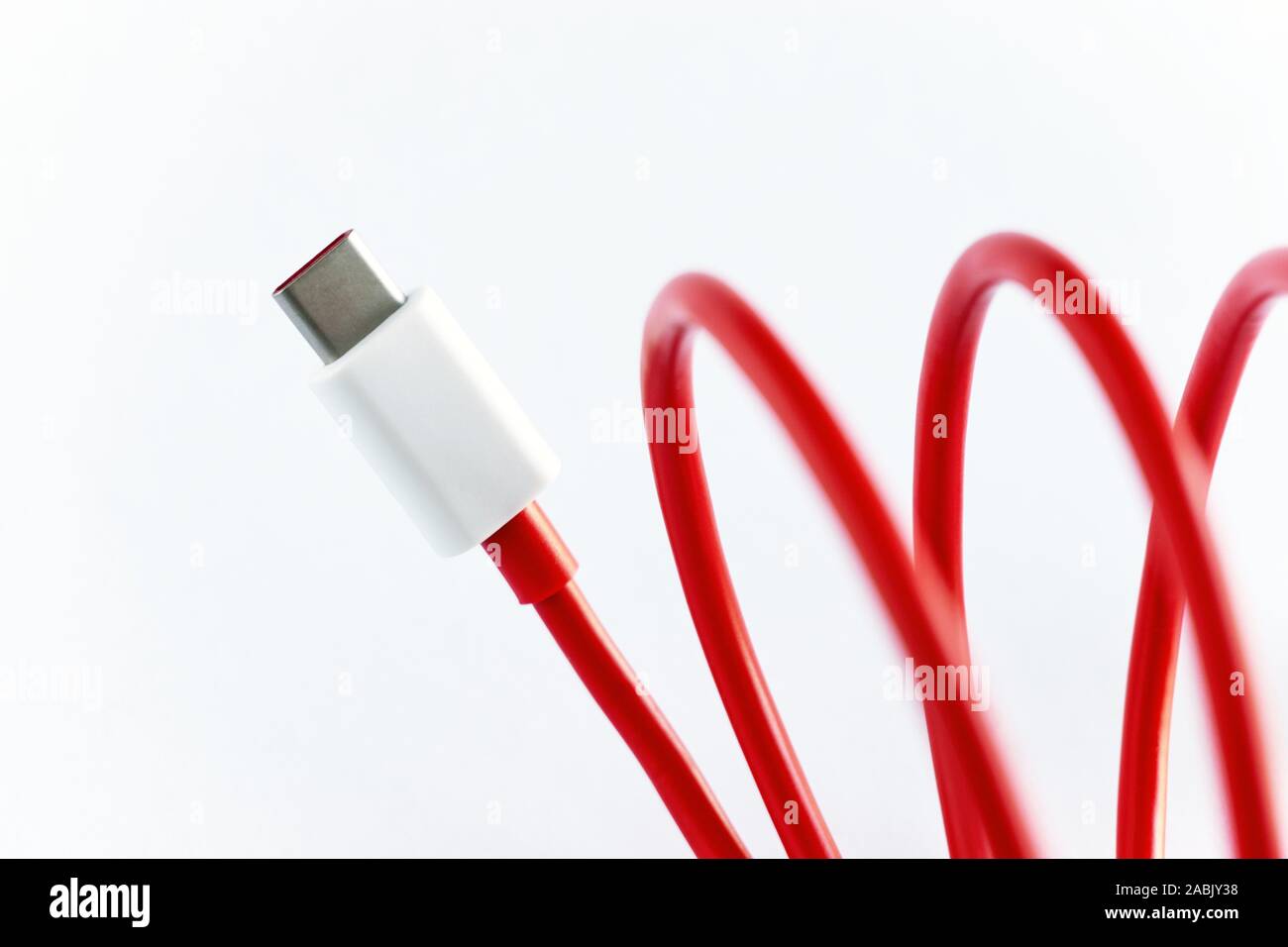 Close-up di rosso arrotolato tipo USB-C del cavo su sfondo bianco Foto Stock