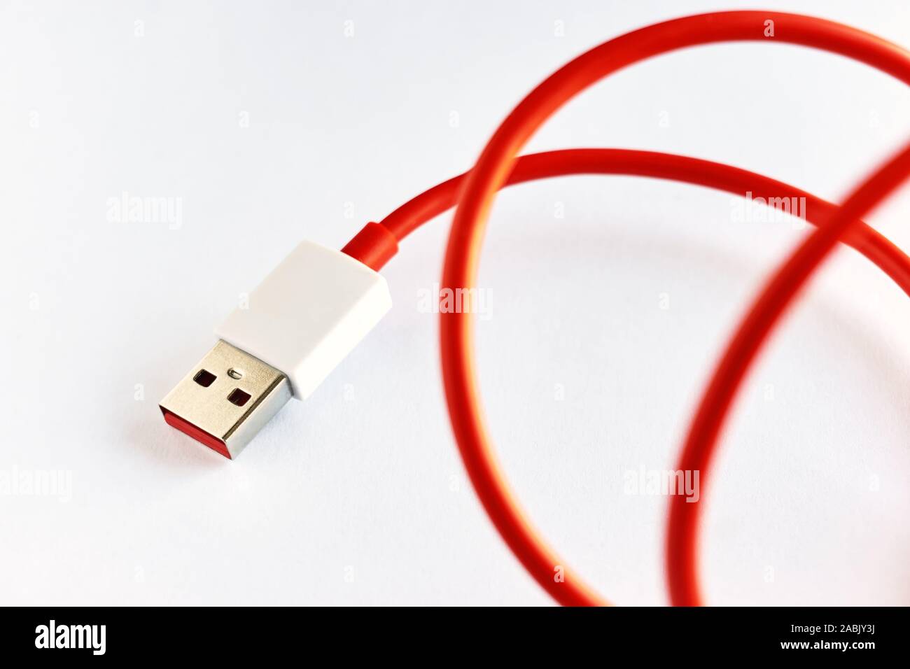 Close-up di red arricciata cavo USB su sfondo bianco Foto Stock