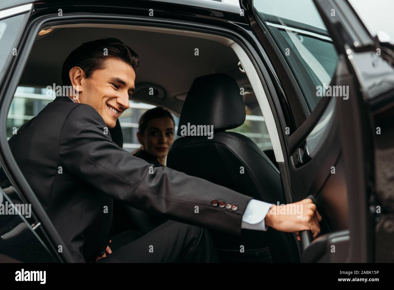 Imprenditore sorridente chiusura porta passeggero del taxi Foto Stock