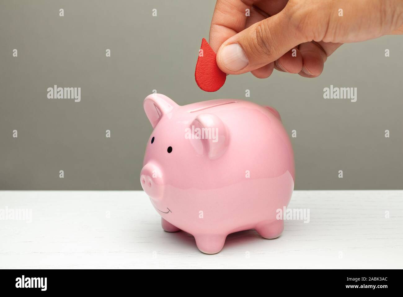 Le donazioni di sangue. L'uomo mette goccia di sangue nel salvadanaio. Foto Stock