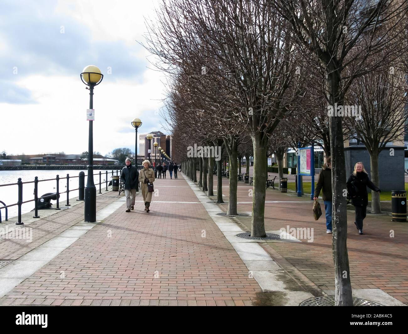 La gente che camminava sul marciapiede accanto al bacino di Ontario, Manchester Ship Canal, le banchine, Salford, Manchester, Inghilterra, Regno Unito Foto Stock