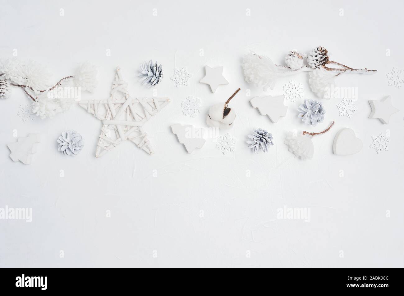 Progettazione di frontiera un Natale biglietto di auguri con il Natale coni, cuore, stelle, fiori di cotone con posto per il vostro testo. Decorazioni su un legno bianco Foto Stock