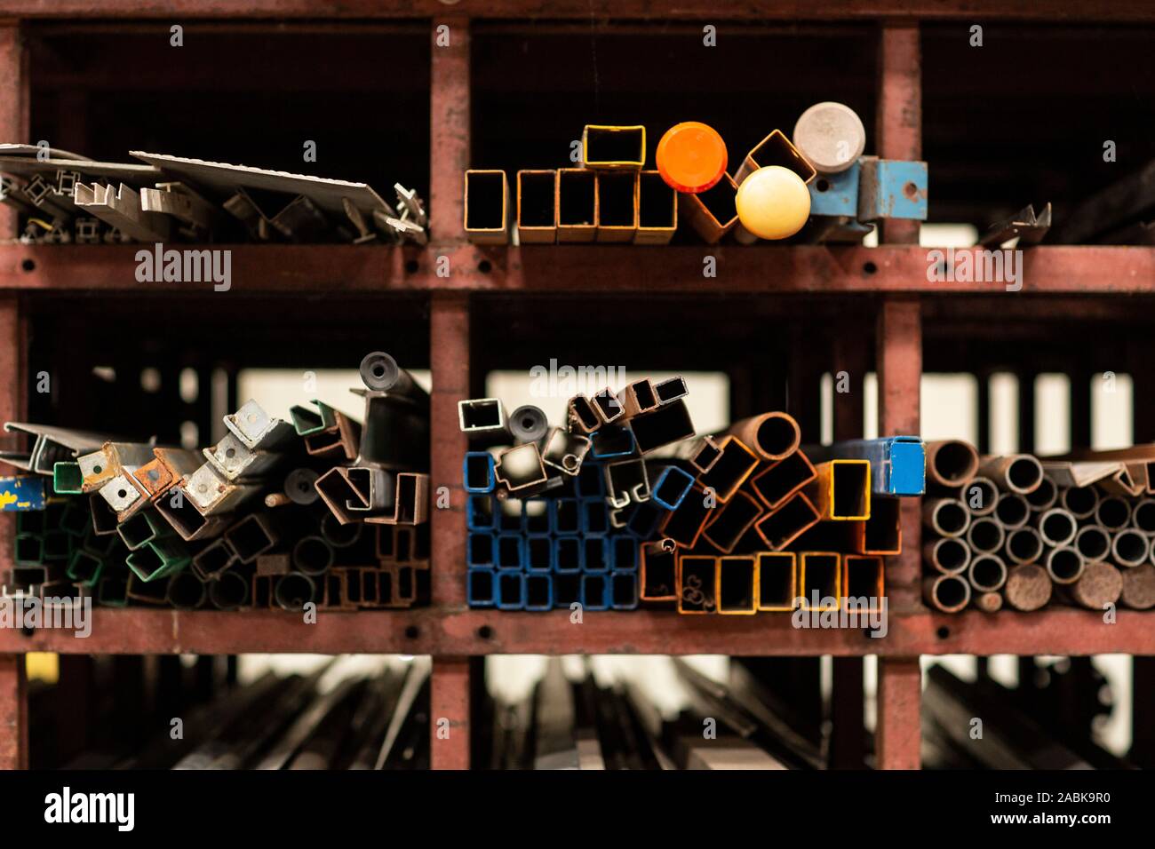 Un dettaglio di diversi stili e dimensioni del vecchio metallo riciclato di tubi e profili dei materiali da costruzione la posa sul ripiano di un rack in un magazzino riciclato m Foto Stock