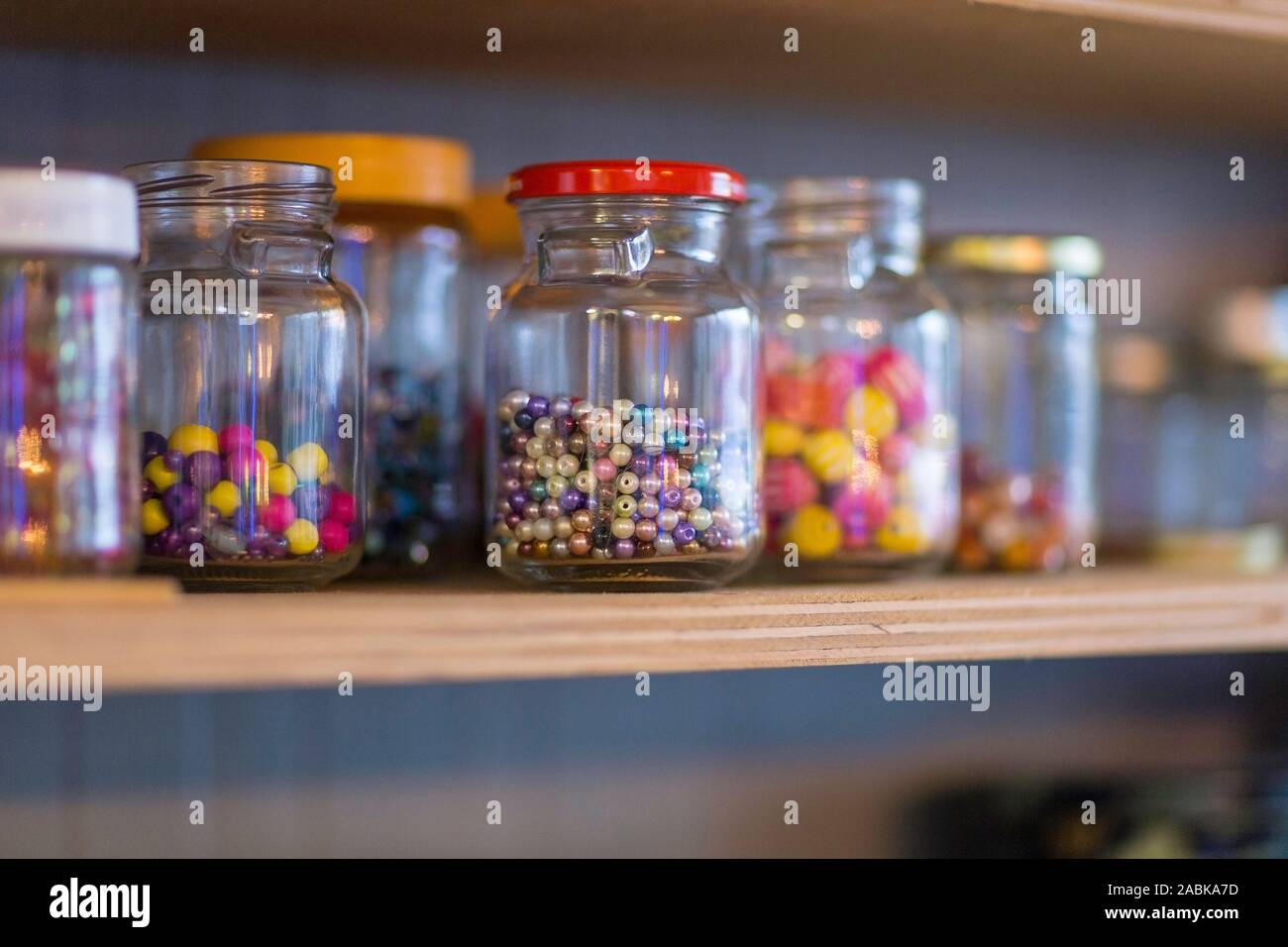 Un dettaglio di carta riciclata per vasi di vetro con diverse dimensioni di perline colorate al loro interno su un ripiano. Circolare principio di economia, il riciclaggio, il riutilizzo Foto Stock