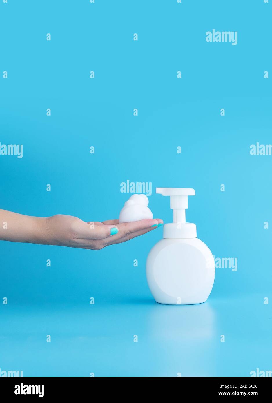 Pompa in plastica bottiglia e mousse schiuma o schiuma detergente sulla donna canto isolato su sfondo blu, verticale con copia spazio. Il concetto di pulizia Foto Stock