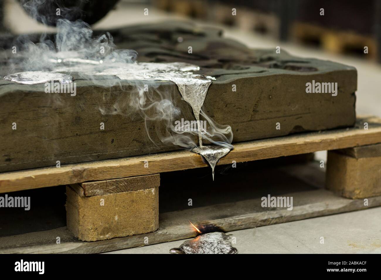 Metallo sabbia tecnica di colata colata di alluminio fuso colore argento liquido in uno stampo mentre si effettua il fumo in un ambiente industriale, spazio officina Foto Stock Metallo sabbia tecnica di colata colata di alluminio fuso colore argento liquido in uno stampo mentre si effettua il fumo in un ambiente industriale, spazio officina Foto Stock
