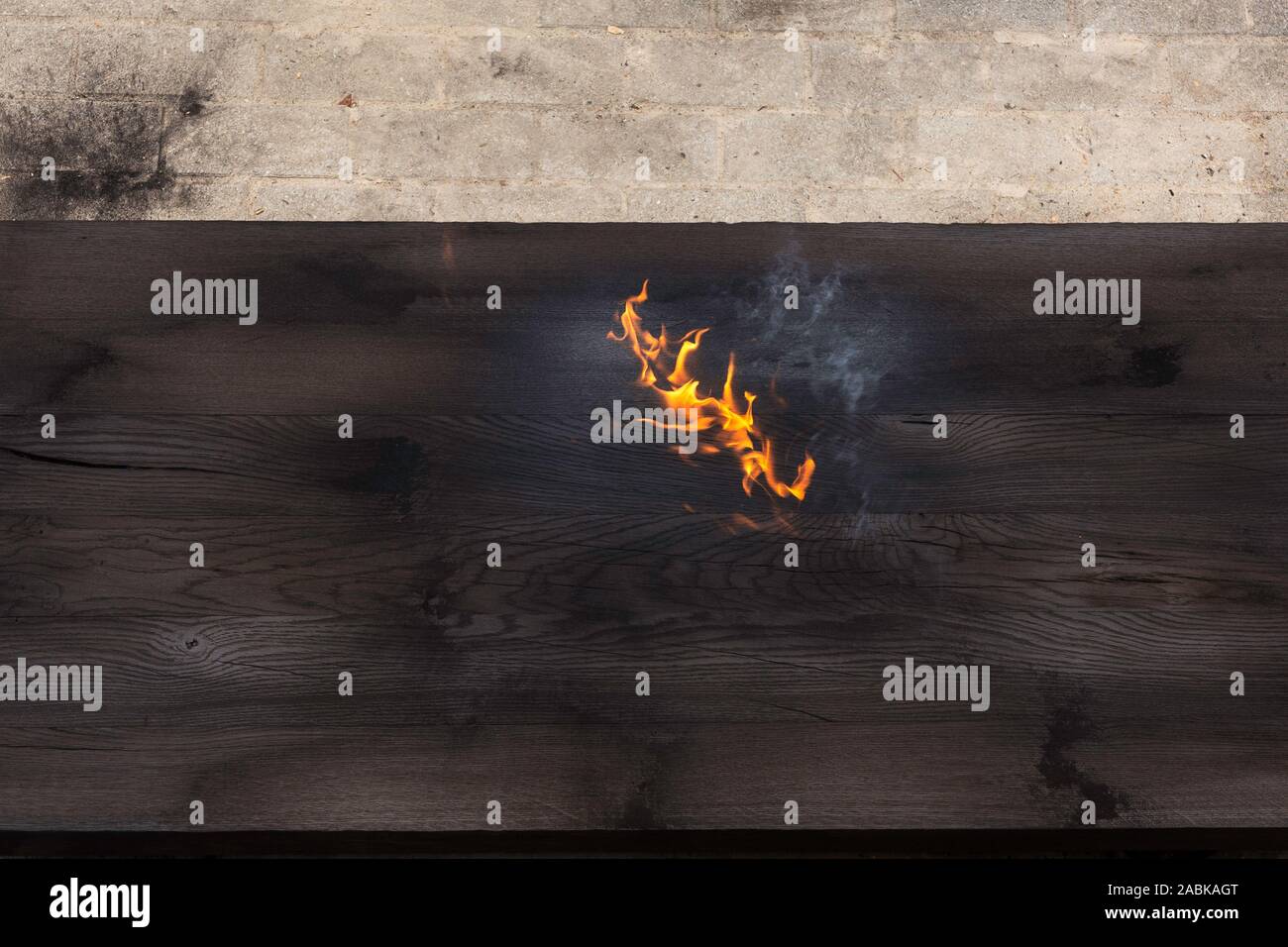 Dettaglio della masterizzazione di un grosso pezzo di legno di quercia, appena bruciato con una torcia di fuoco, creazione di fiamme e fumo, vecchia jappanese shou sugi divieto tecnica woode nero Foto Stock