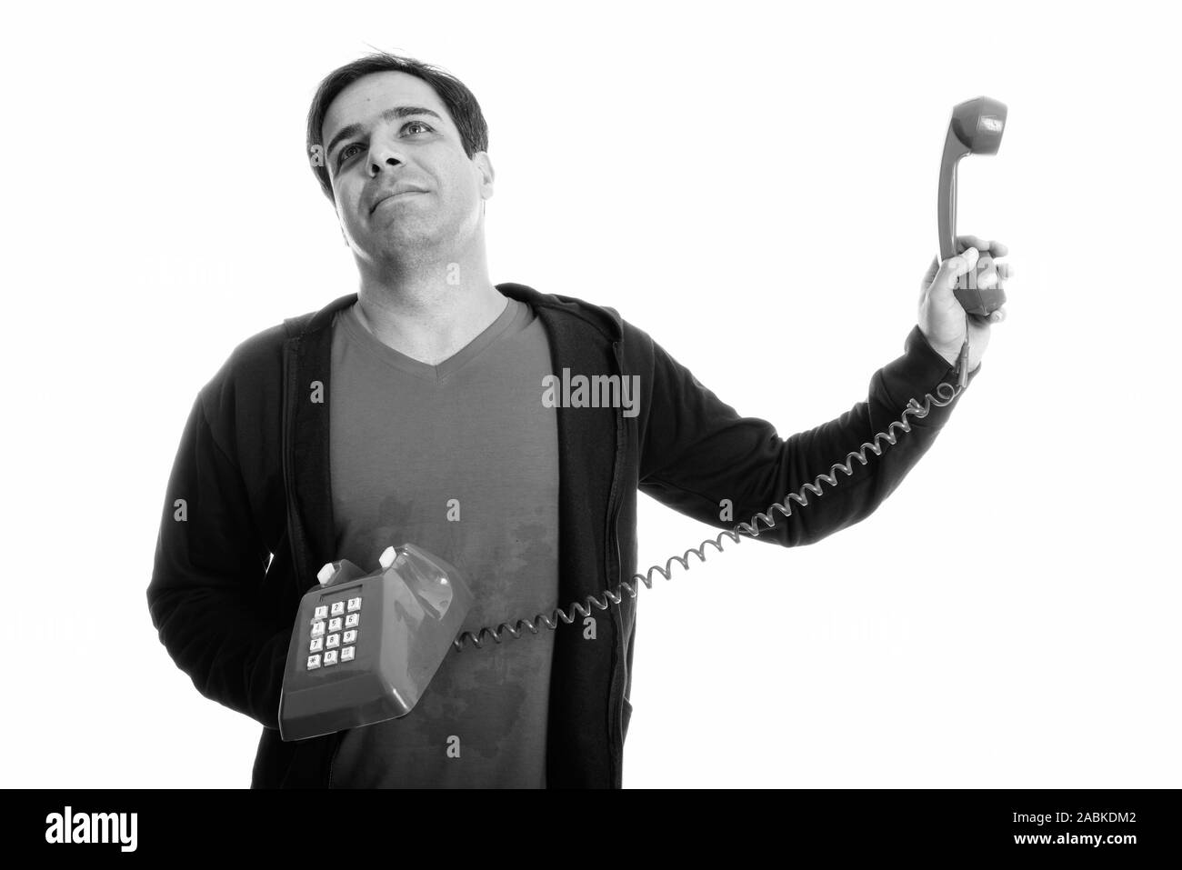 Studio shot di pensosa giovane uomo persiano tenendo il vecchio telefono lontano mentre guardando infastiditi Foto Stock