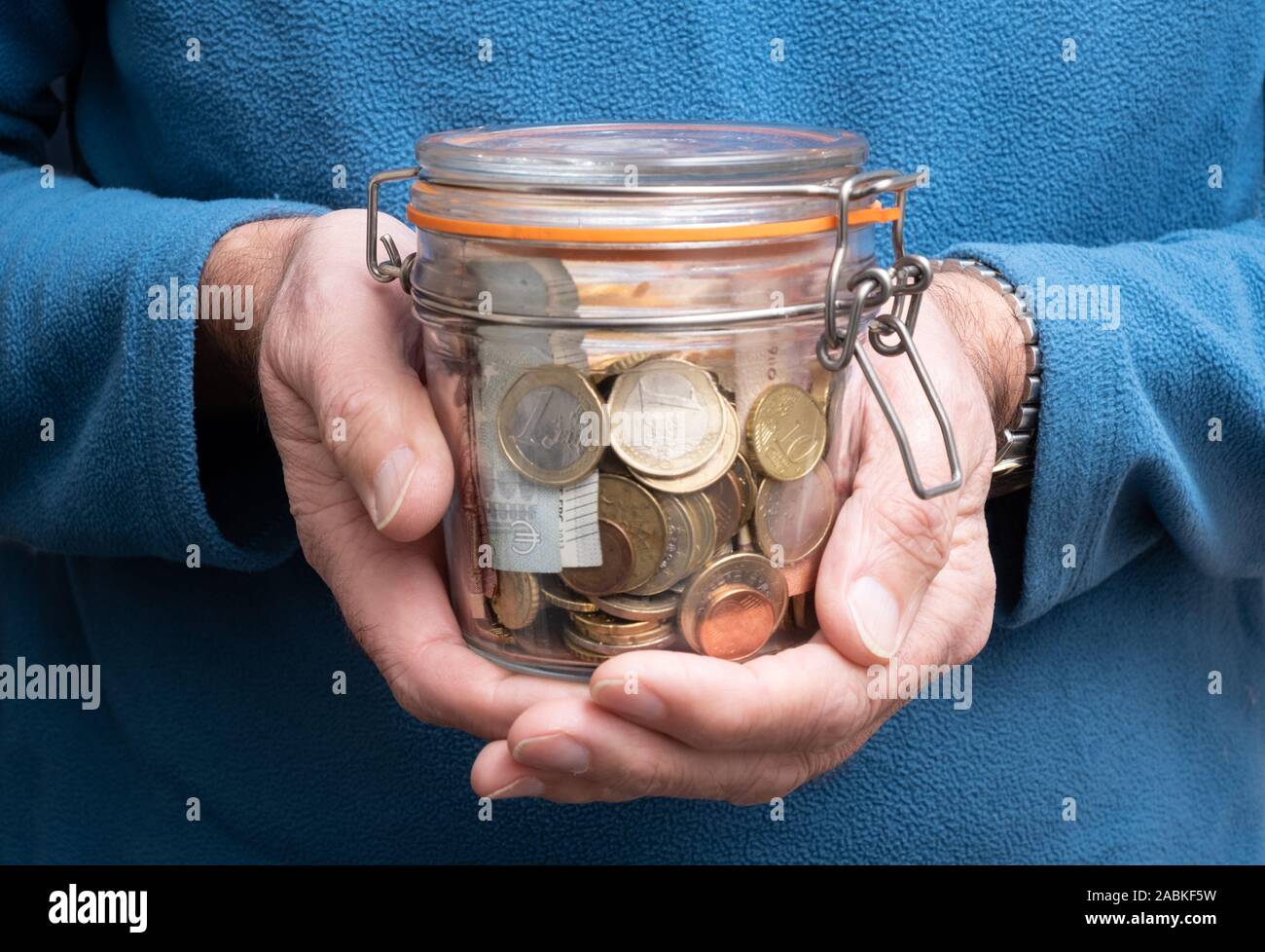 L'uomo mani tenendo il vaso pieno di euro denaro, il concetto di fondo pensione, monete e banconote in euro Foto Stock