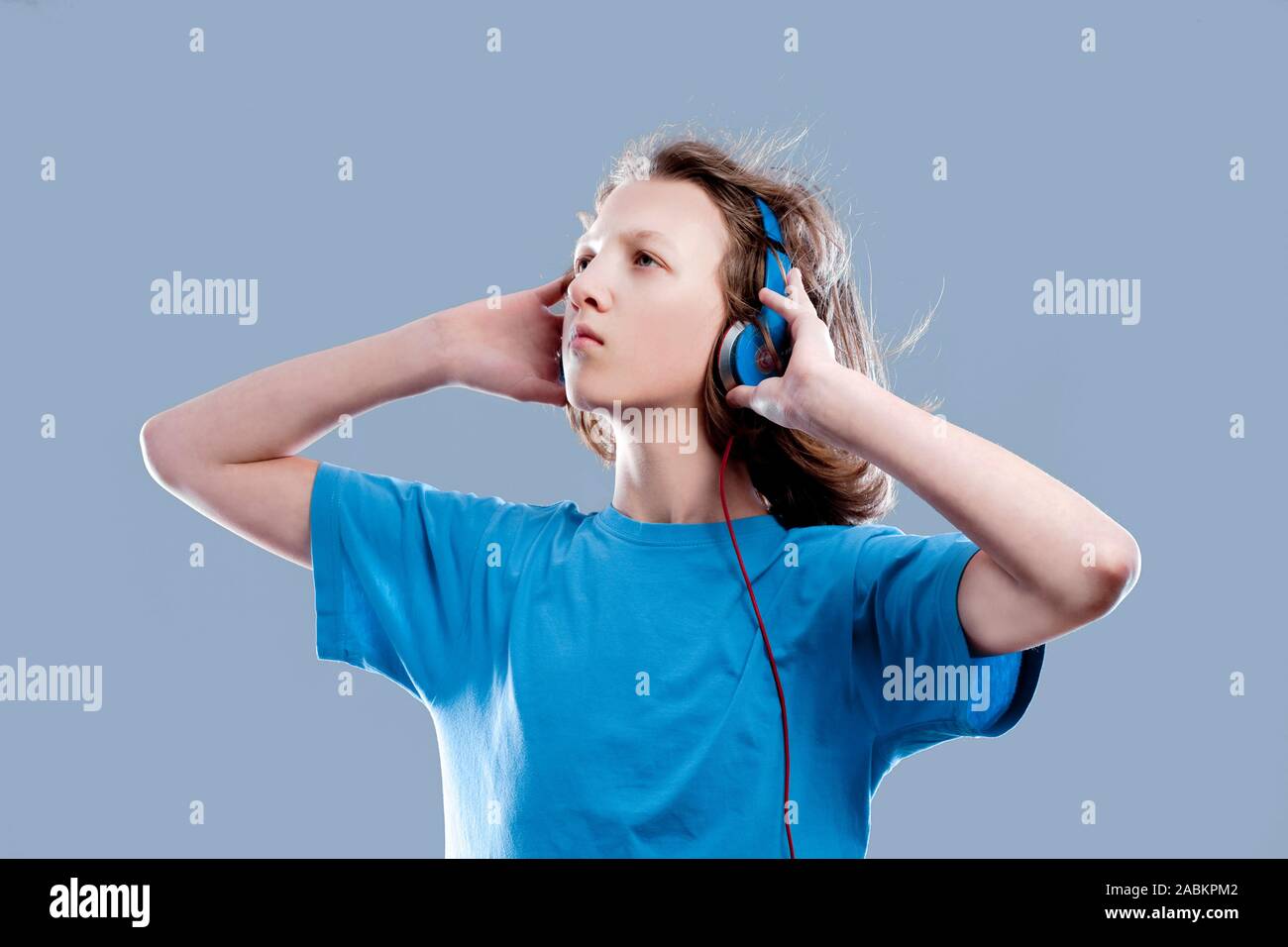 Ragazzo con capelli castani ascoltando la musica nelle cuffie. Foto Stock