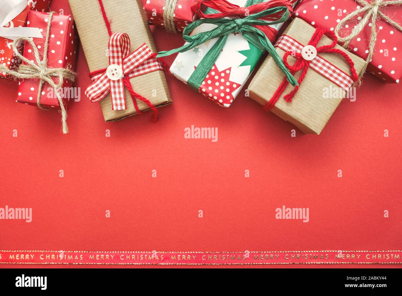 Natale biglietto di auguri con diverse confezioni regalo su sfondo rosso. Vista da sopra con copia spazio. Foto Stock