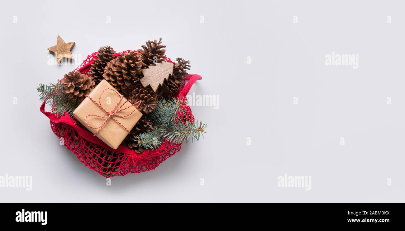 Natale rifiuti zero decor in cotone rosso sacchetto eco su grigio. Coni e Abete rami per design fatti a mano. Foto Stock