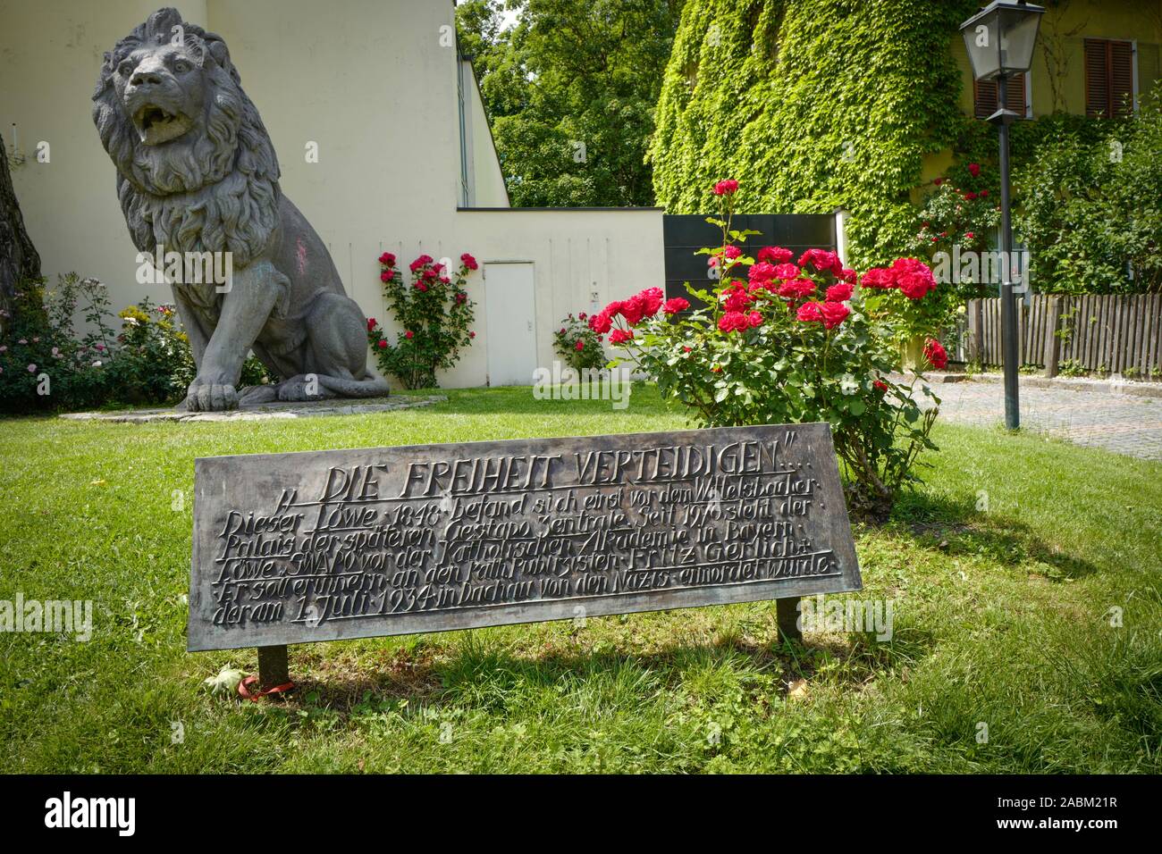 Statua di un leone di fronte all'Accademia cattolica in Mandlstraße 23. È utilizzato per stare di fronte al Wittelsbacher Palais, il Monaco di Baviera sede della Gestapo durante il nazismo. L'iscrizione commemora la resistenza fighter Fritz Gerlich, che è stato assassinato nel campo di concentramento di Dachau nel 1934. [Traduzione automatizzata] Foto Stock