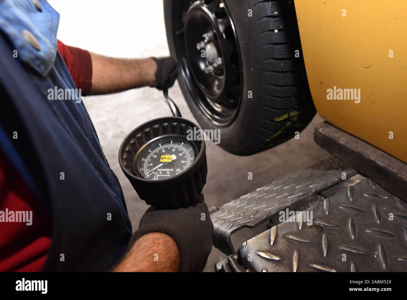 Un partecipante da KFZ Mechatronik modifiche pneumatici vettura nell'ala di workshop e controlla la pressione di gonfiaggio dei pneumatici. [Traduzione automatizzata] Foto Stock