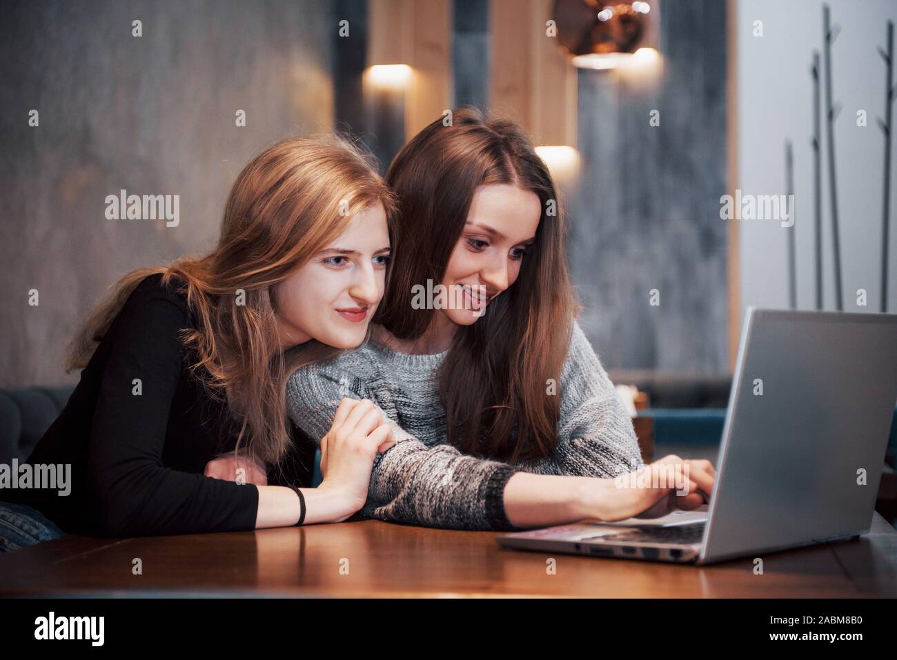 Due ragazze navigando in rete, la pubblicazione su reti sociali su un computer portatile e divertirsi Foto Stock
