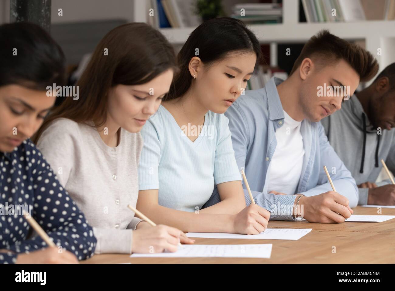 Concentrato di razza mista agli studenti di passare un esame di valutazione durante la sessione. Foto Stock