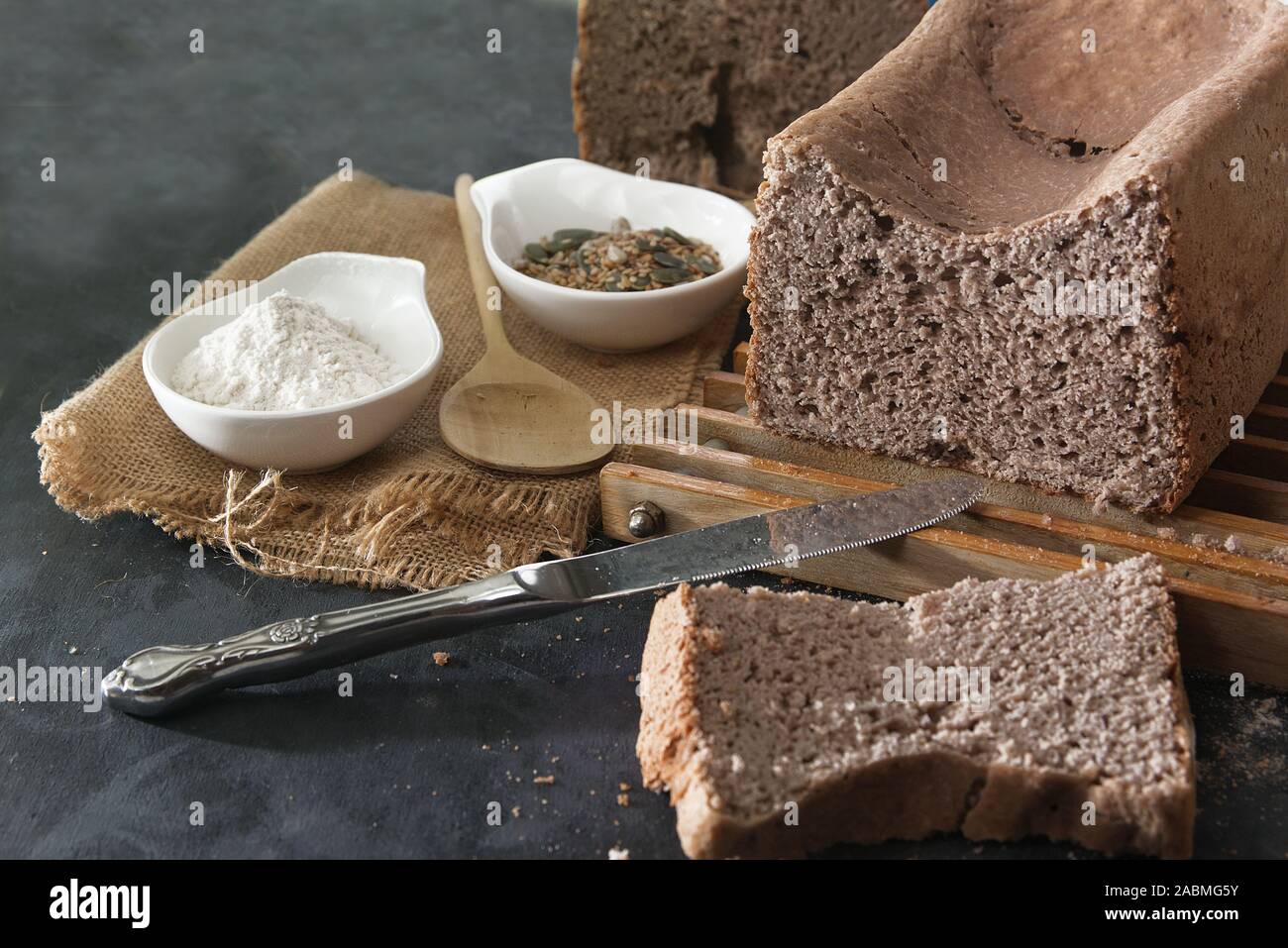 In casa cereali integrali di grano saraceno a fette di pane su una tavola di legno in una cucina rustica. Accanto, il sacco, il cucchiaio e il frumento. Svuotare lo spazio di copia per l'editor di testo Foto Stock