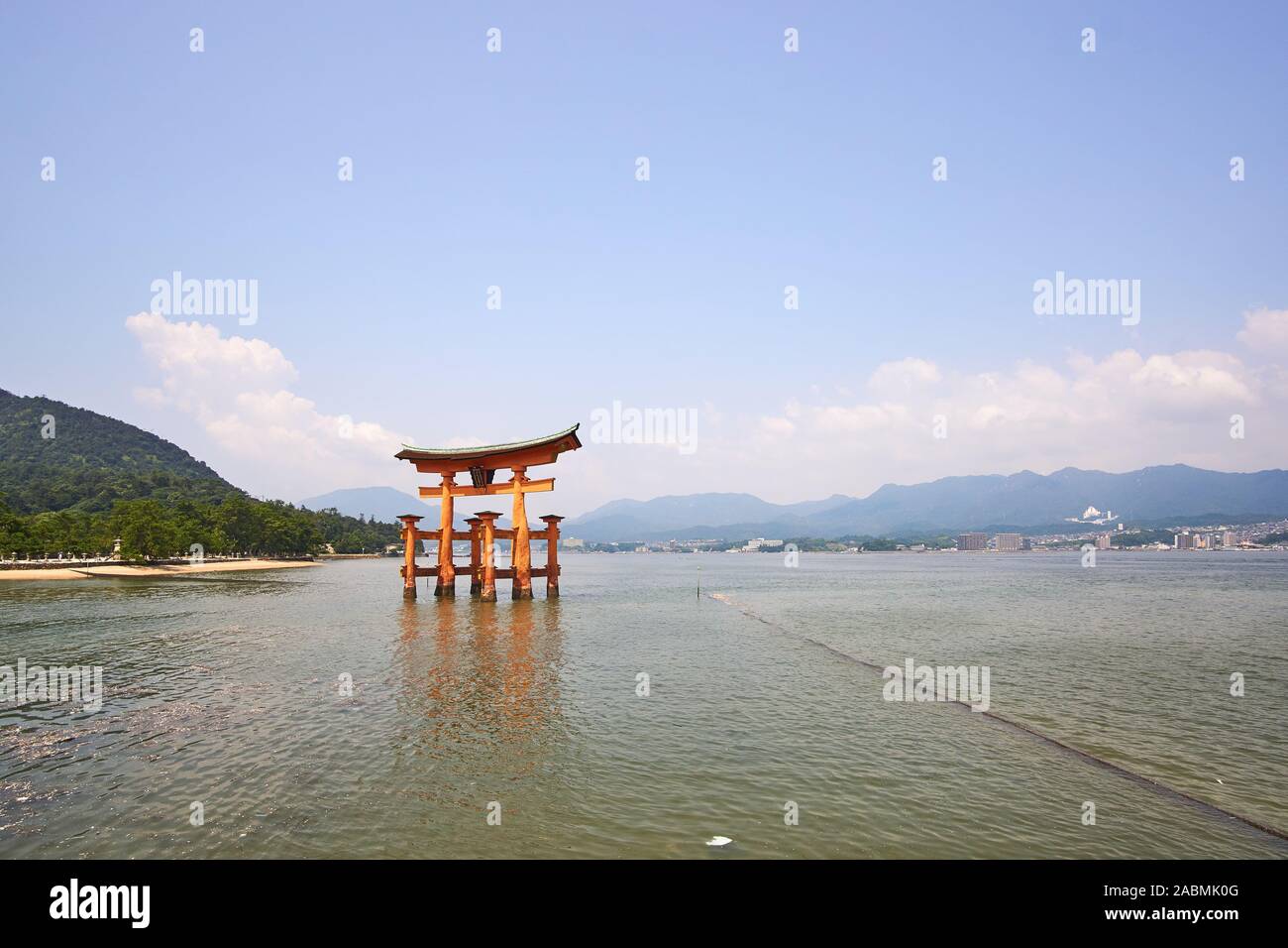 Il vermiglio torii gate del santuario di Itsukushima Jinja Santuario su Miyajima sorge nell'acqua ad alta marea con le montagne sullo sfondo Foto Stock