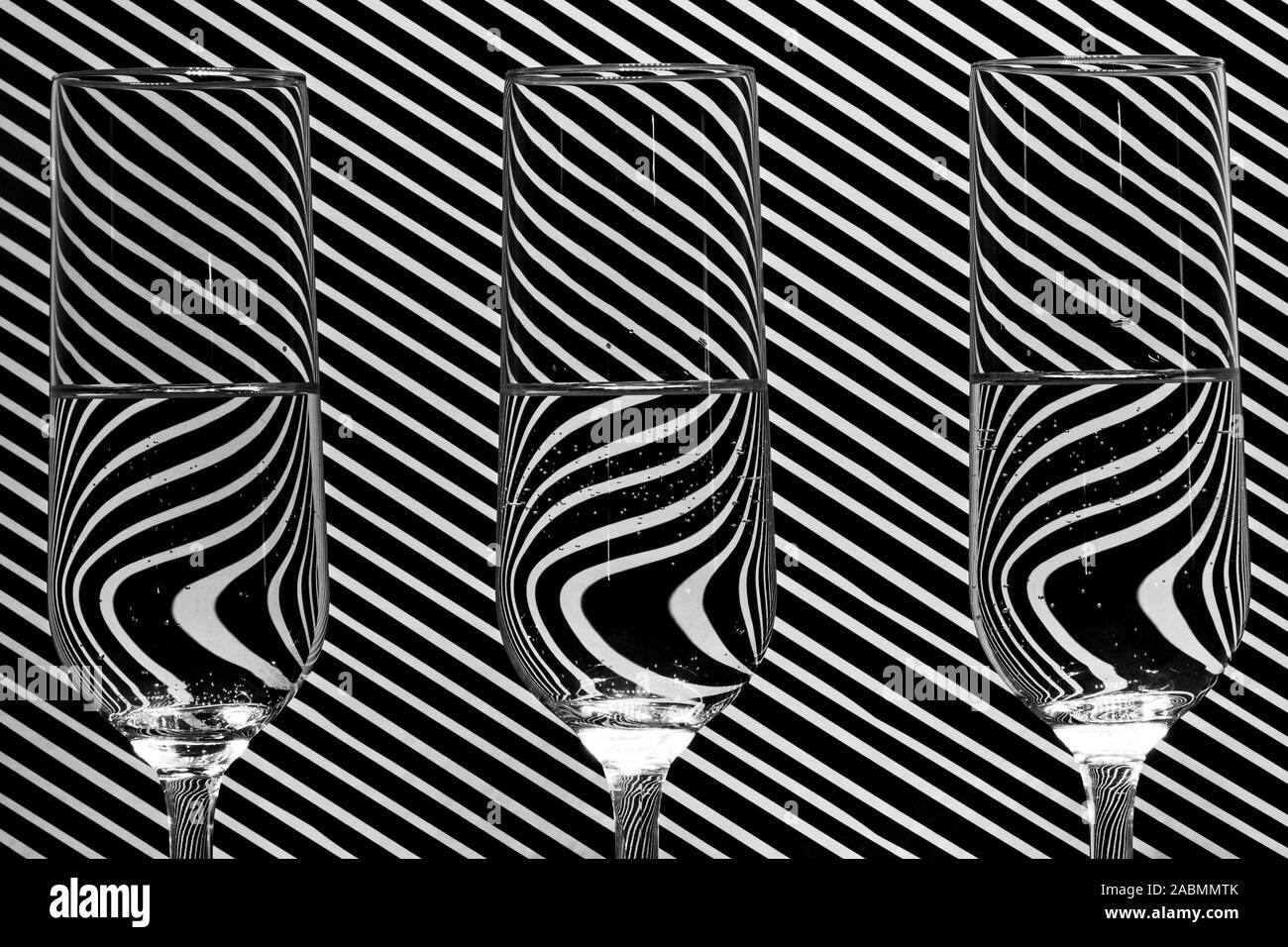 Immagine dei tre champagne riempito di vetro con acqua nella parte anteriore di uno sfondo con una linea diagonale pattern, con uno specchio di riflessione nel bicchiere Foto Stock