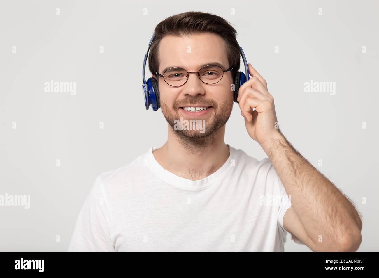 Sorridente ragazzo millenario ascoltare musica con gli auricolari Bluetooth Foto Stock