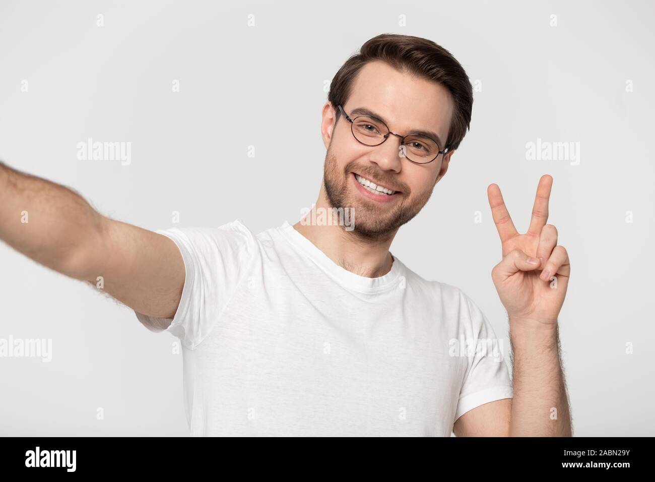 Sorridente uomo millenario in vetri rendono selfie in studio Foto Stock