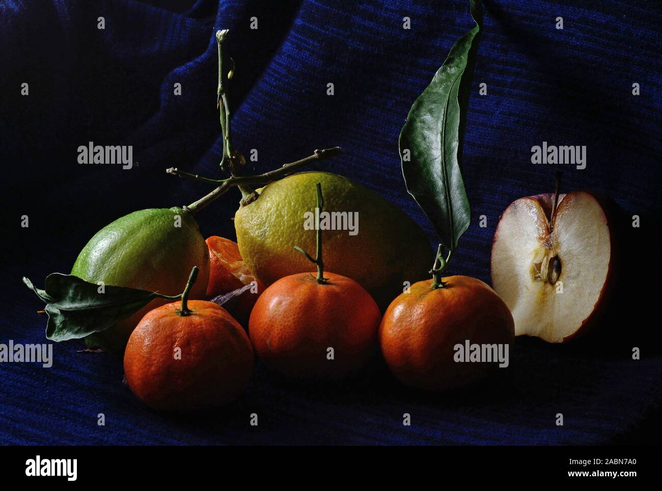 Limone e frutta tamiringe con una mezza mela su uno sfondo blu scuro Foto Stock