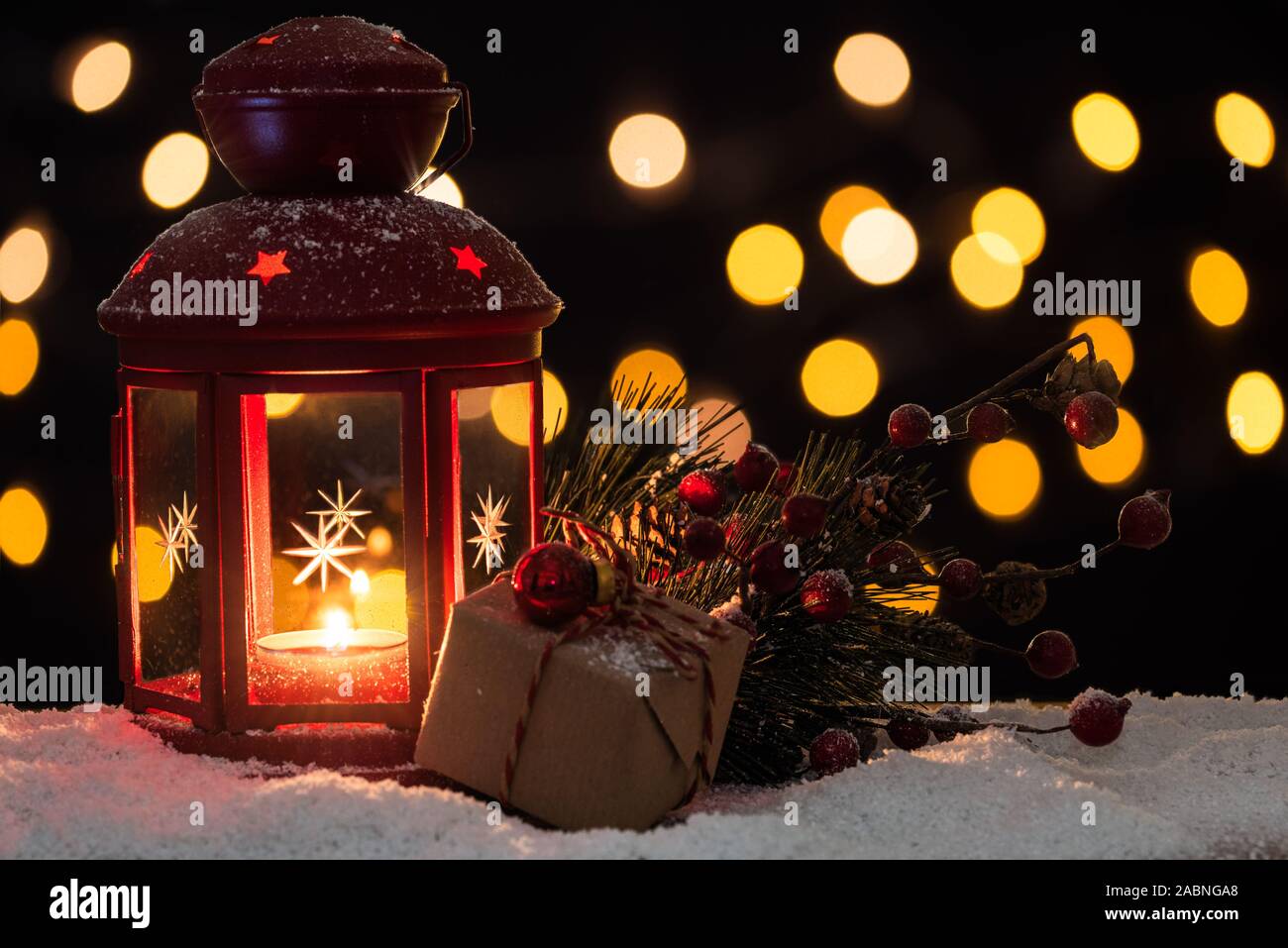 Lanterna di natale e decorazioni sulla neve con luci sfocate in background. Messa a fuoco selettiva e copia dello spazio. Foto Stock