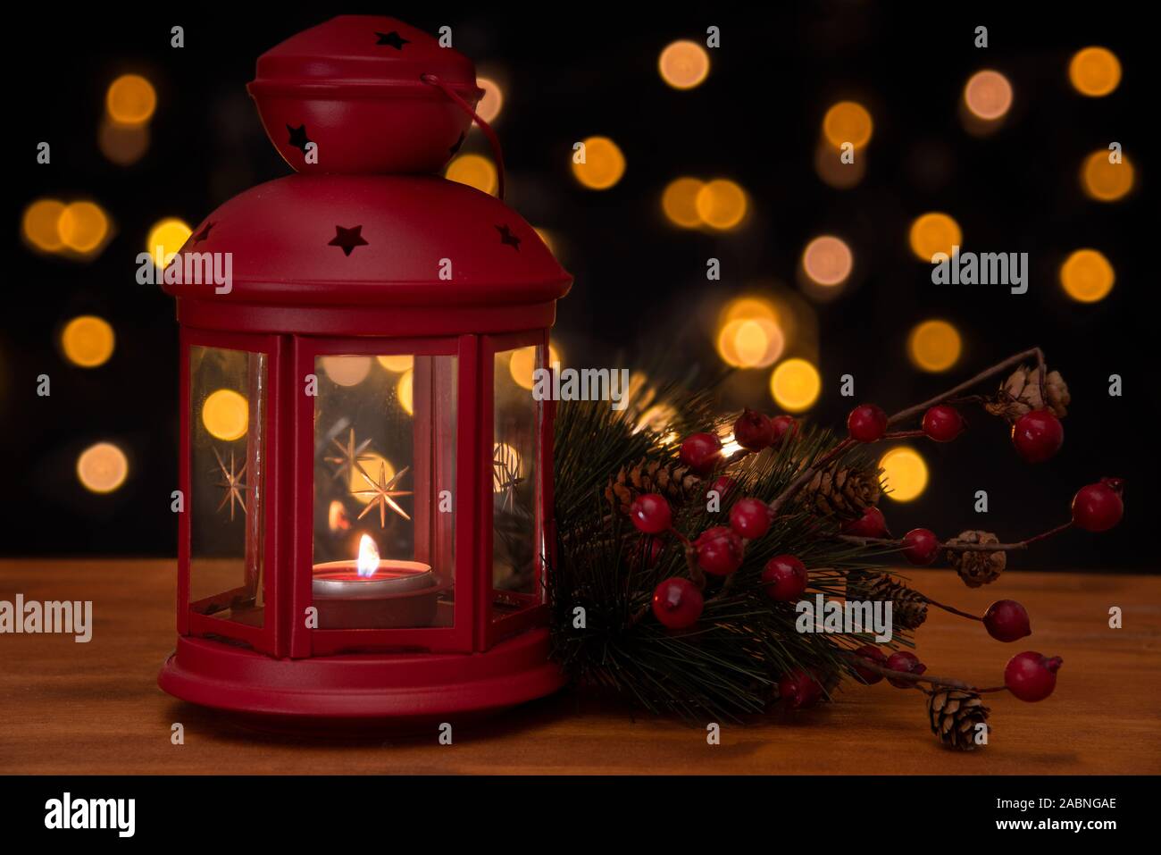 Rosso lanterna di Natale e un pino brach su un tavolo di legno con luci sfocate in background. Slective focus e copia dello spazio. Foto Stock