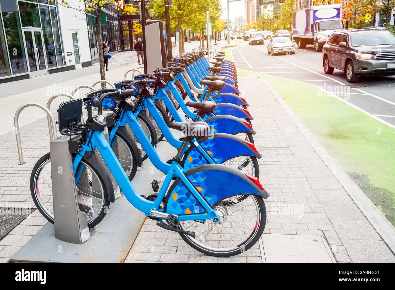 Share-uso biciclette in una docking station lungo la trafficata strada con una pista ciclabile Foto Stock