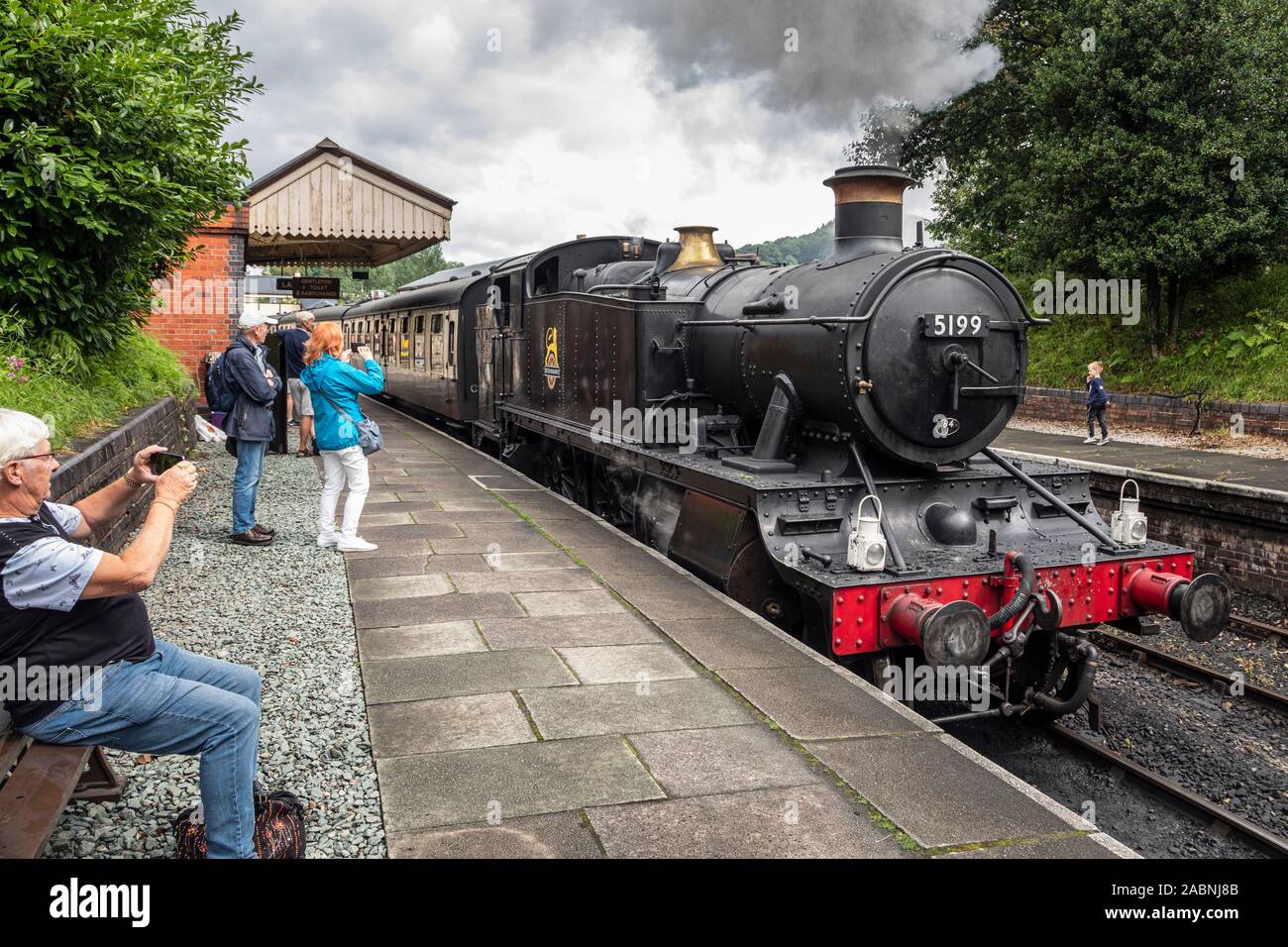 I turisti a guardare un motore a vapore lasciando la stazione di Llangollen, Llangollen Railway, Denbighshire, Galles Foto Stock