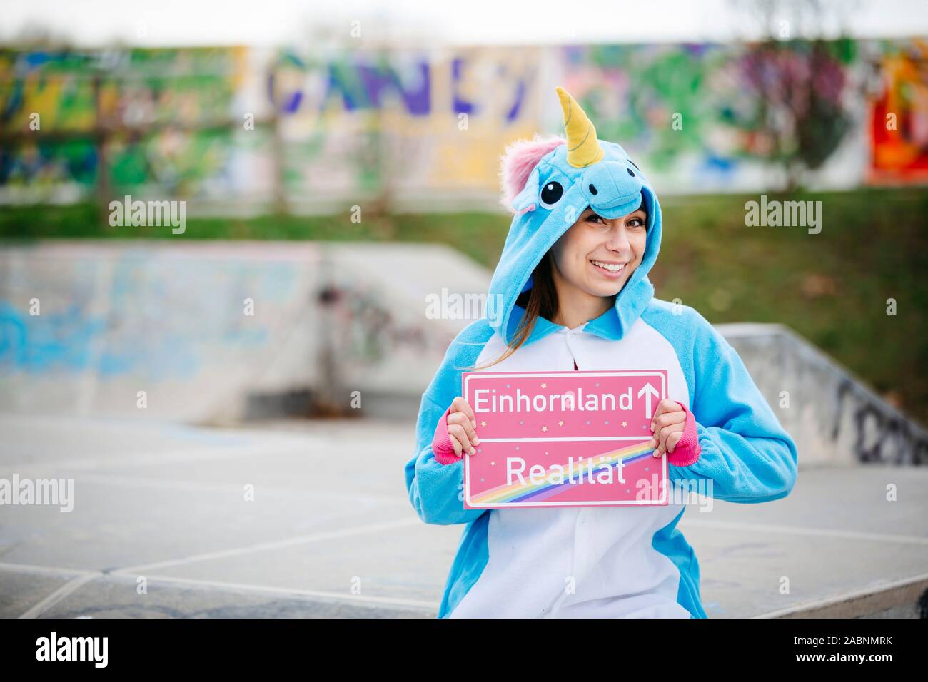 Giovane e bella donna che indossa il turchese unicorn onesie in ambiente urbano Foto Stock